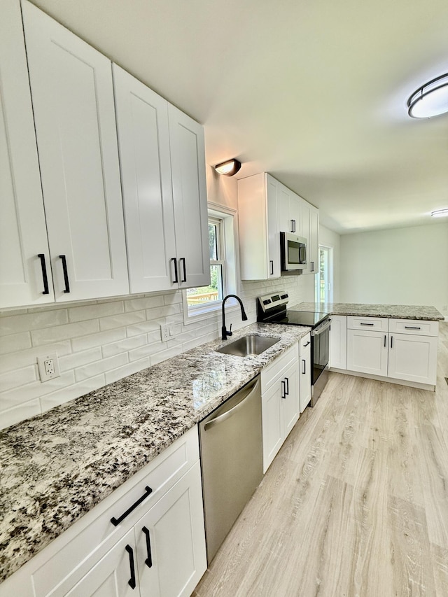 459 Pocono Blvd, Bushkill, PA 18324 - kitchen with appliances with stainless steel finishes, light wood-type flooring, tasteful backsplash, light stone countertops, and white cabinets