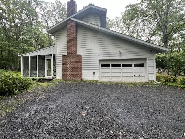 122 Savage Trl, East Stroudsburg, PA 18301 - view of property exterior featuring a chimney, asphalt driveway, and a sunroom