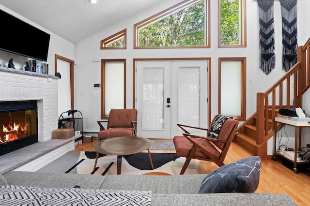 130 Ruffed Grouse Rd, Bushkill, PA 18324 - living area featuring wood finished floors, a brick fireplace, french doors, high vaulted ceiling, and stairs