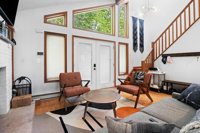 130 Ruffed Grouse Rd, Bushkill, PA 18324 - living room featuring wood finished floors, stairway, baseboard heating, a high ceiling, and a brick fireplace