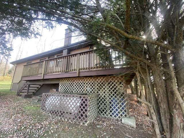 view of side of home with a chimney, a deck, and stairs