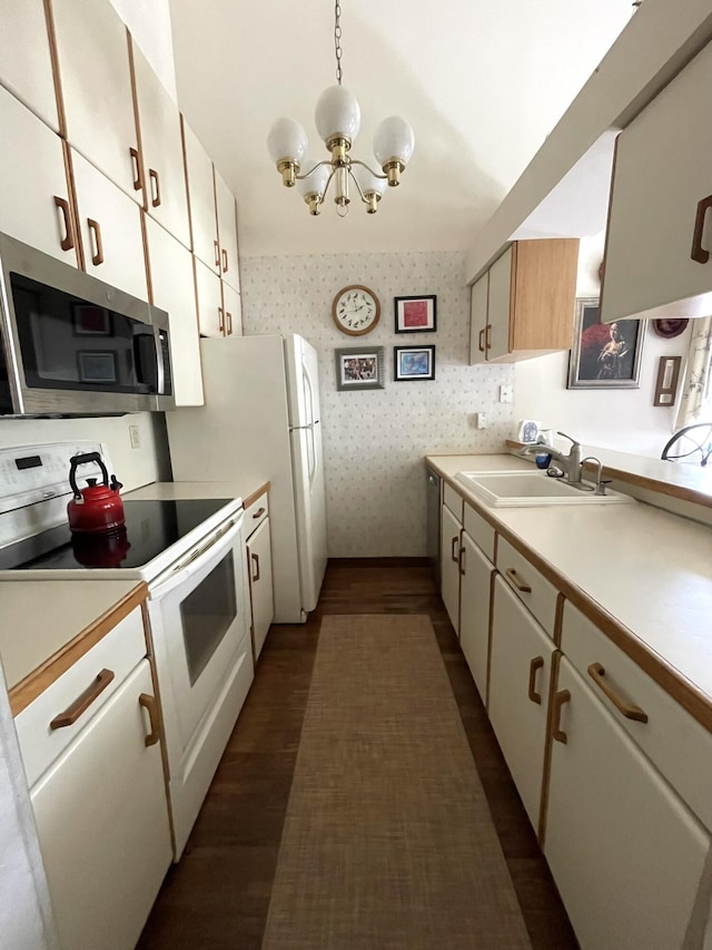 kitchen with white electric range oven, wallpapered walls, a sink, light countertops, and stainless steel microwave