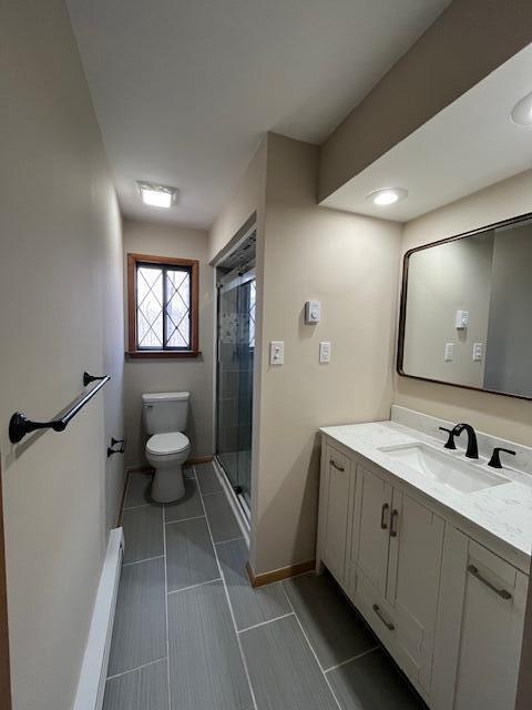 bathroom featuring baseboards, toilet, a stall shower, and vanity