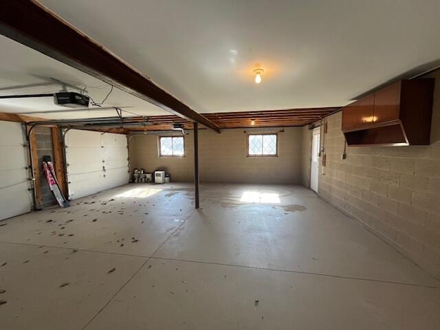 garage featuring a garage door opener and concrete block wall