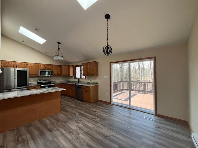 kitchen with brown cabinets, appliances with stainless steel finishes, a skylight, and pendant lighting