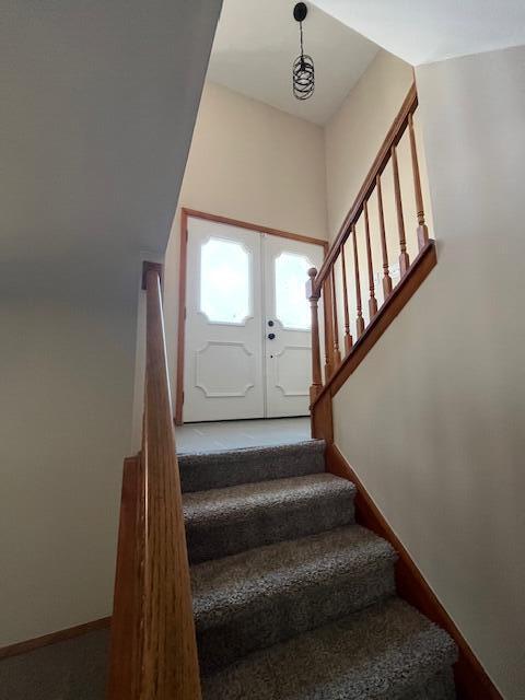 stairway with french doors and baseboards