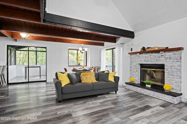 living room featuring vaulted ceiling with beams, hardwood / wood-style flooring, a fireplace, and a chandelier