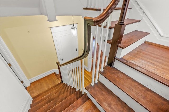 stairs featuring baseboards, wood finished floors, and beamed ceiling