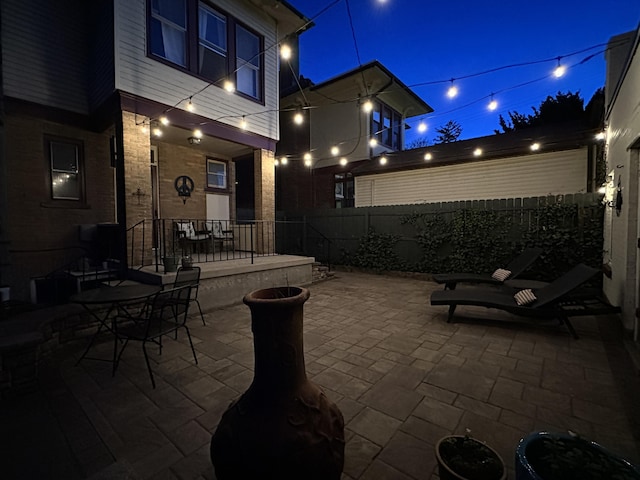 patio at twilight featuring fence