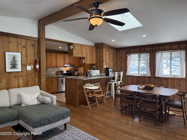 1827 Stag Run, Pocono Lake, PA 18347 - dining area featuring wooden walls, vaulted ceiling with skylight, light wood-type flooring, and a ceiling fan