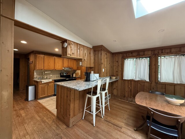 1827 Stag Run, Pocono Lake, PA 18347 - kitchen featuring light wood finished floors, vaulted ceiling, dishwasher, backsplash, and brown cabinetry