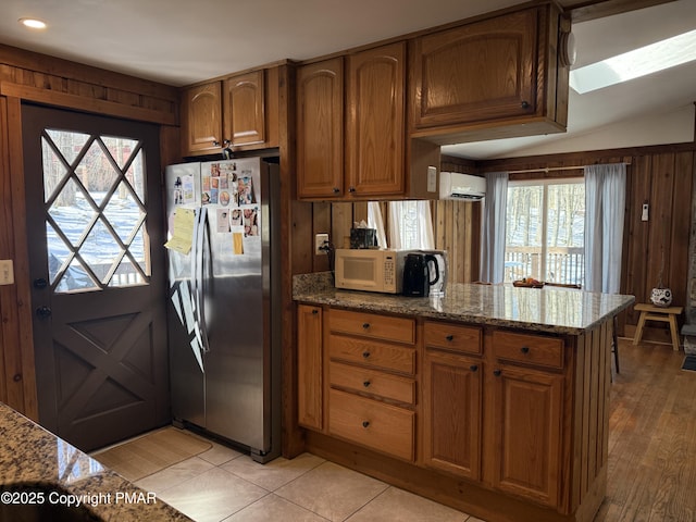 1827 Stag Run, Pocono Lake, PA 18347 - kitchen featuring stainless steel refrigerator with ice dispenser, a wall unit AC, healthy amount of natural light, a peninsula, and wooden walls