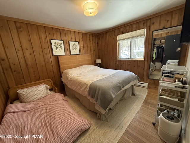 1827 Stag Run, Pocono Lake, PA 18347 - bedroom featuring wooden walls, a baseboard heating unit, light wood finished floors, and a closet