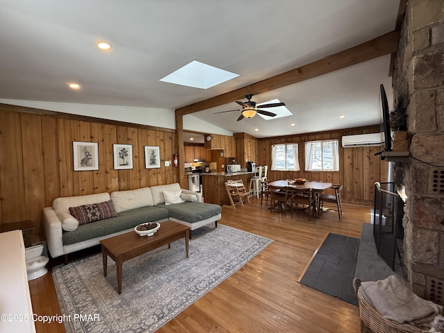 1827 Stag Run, Pocono Lake, PA 18347 - living area featuring wooden walls, ceiling fan, lofted ceiling with skylight, a wall mounted air conditioner, and light wood-style floors