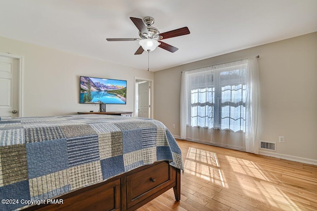 bedroom featuring light wood finished floors, baseboards, visible vents, and ceiling fan