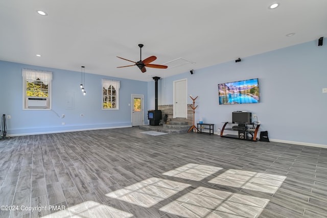 unfurnished living room featuring baseboards, a ceiling fan, a wood stove, light wood-type flooring, and recessed lighting