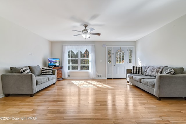 living area with light wood finished floors, ceiling fan, visible vents, and baseboards