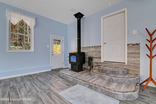 living area featuring wood finished floors, a wood stove, and baseboards