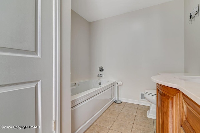 bathroom featuring a garden tub, toilet, vanity, tile patterned flooring, and baseboards