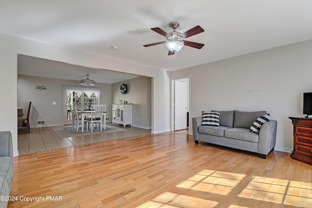 unfurnished living room with ceiling fan, wood finished floors, and baseboards