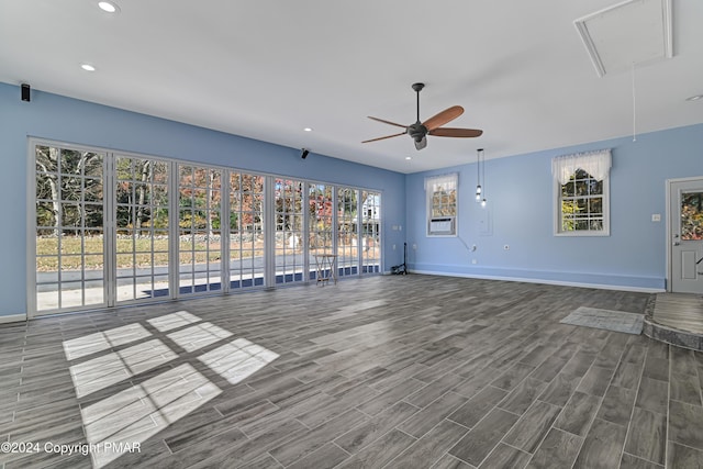 unfurnished living room featuring attic access, baseboards, wood finished floors, and recessed lighting