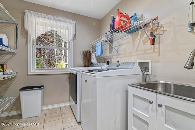 washroom with laundry area, light tile patterned floors, baseboards, independent washer and dryer, and a sink