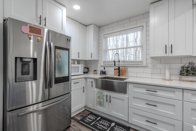 kitchen with stainless steel fridge, white cabinetry, tasteful backsplash, and a sink