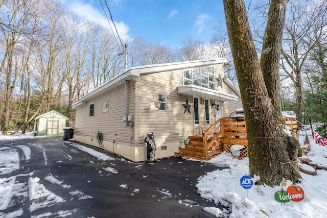 view of snow covered exterior with crawl space and an outdoor structure