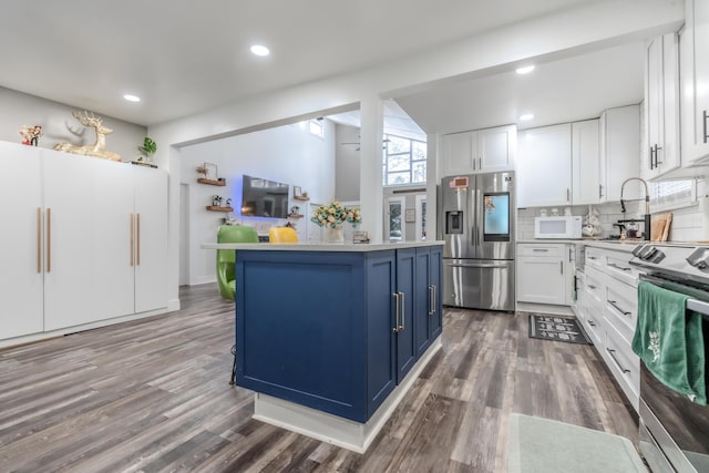 kitchen featuring blue cabinetry, white cabinetry, appliances with stainless steel finishes, and light countertops