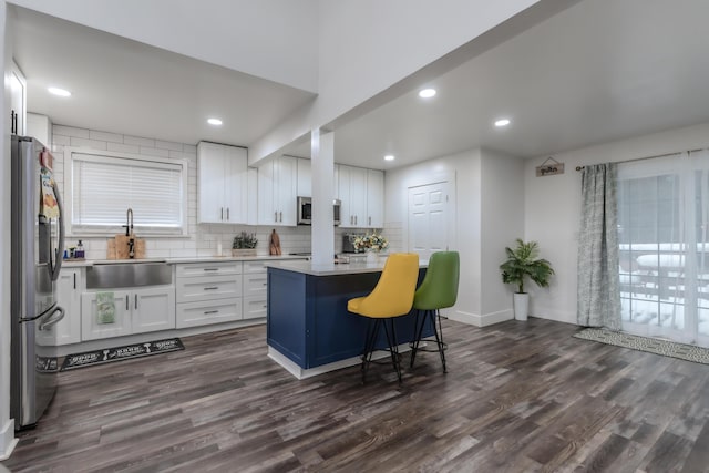 kitchen with appliances with stainless steel finishes, dark wood finished floors, white cabinetry, and a sink