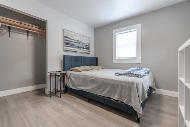 bedroom with a closet, wood finished floors, and baseboards