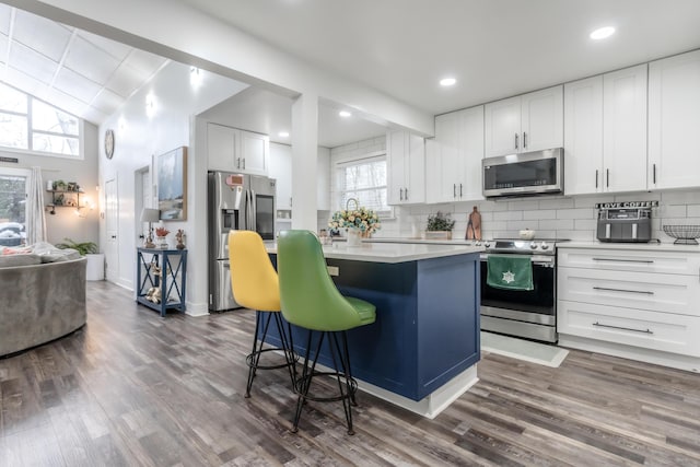 kitchen featuring appliances with stainless steel finishes, a center island, light countertops, and decorative backsplash