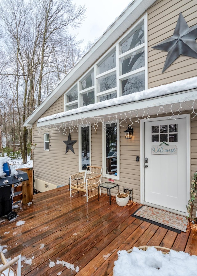 snow covered deck featuring a grill and a porch