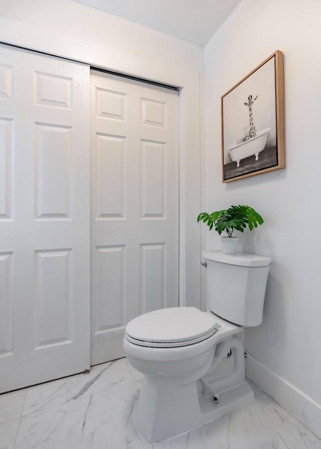 bathroom with toilet, marble finish floor, and baseboards