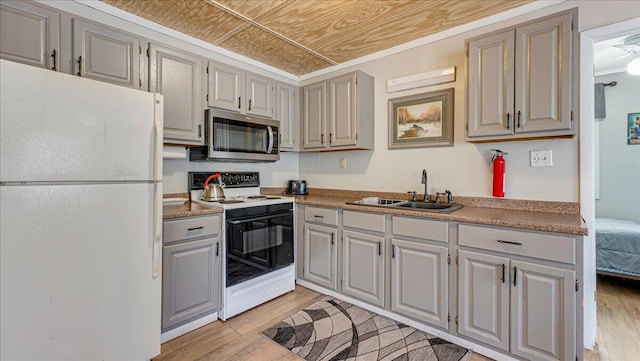 kitchen with range with electric cooktop, gray cabinetry, freestanding refrigerator, stainless steel microwave, and light wood finished floors