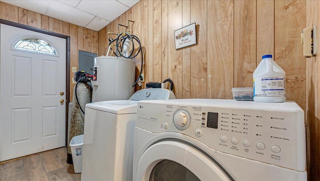 laundry area with independent washer and dryer, wood walls, water heater, wood finished floors, and electric panel