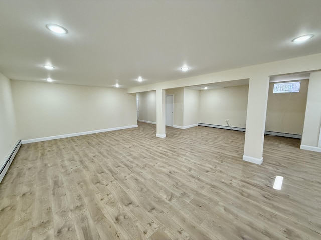 finished basement with baseboard heating, baseboards, light wood finished floors, and recessed lighting