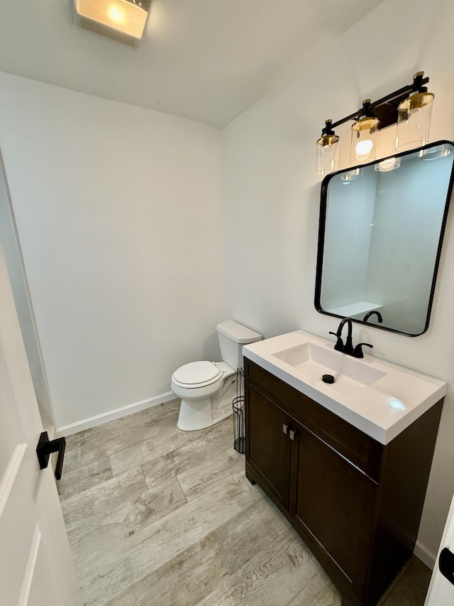 bathroom with baseboards, vanity, toilet, and wood finished floors