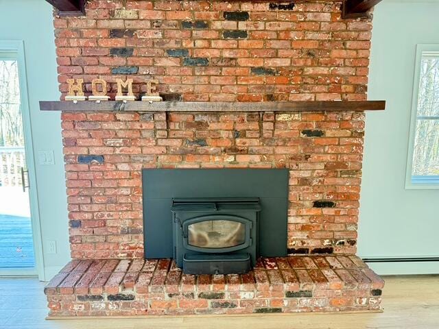 room details featuring baseboard heating, wood finished floors, and a wood stove