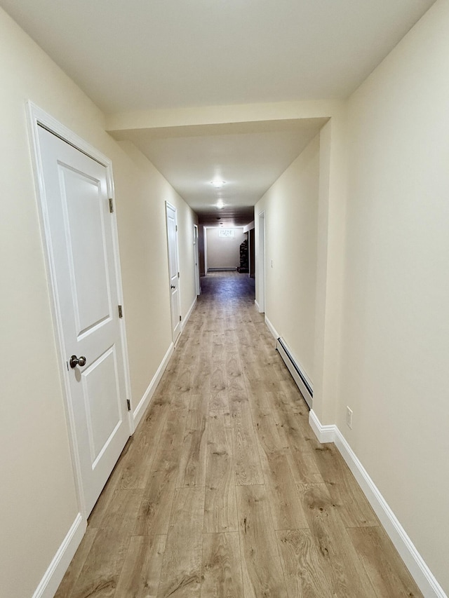 hallway featuring a baseboard heating unit, light wood-type flooring, and baseboards