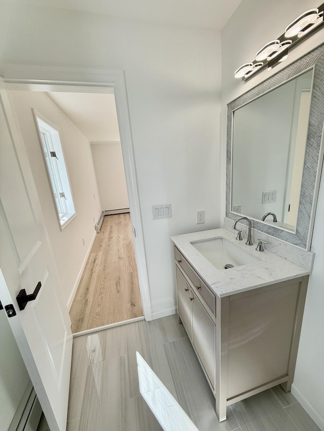 bathroom with baseboards, wood finished floors, and vanity