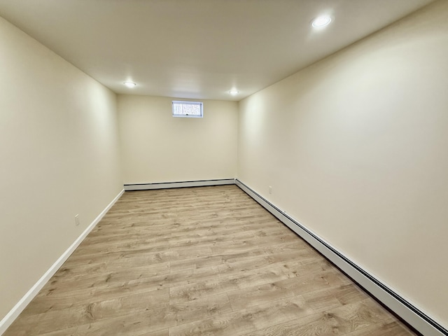 below grade area with a baseboard heating unit, recessed lighting, baseboards, and light wood finished floors