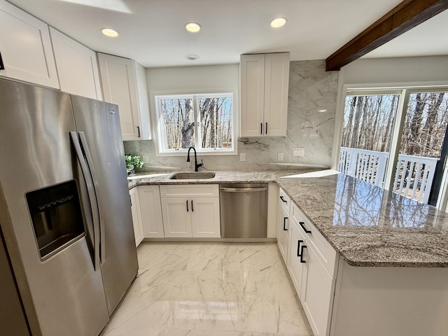 kitchen with marble finish floor, stainless steel appliances, white cabinetry, a sink, and a peninsula