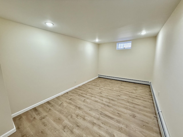 below grade area with recessed lighting, a baseboard radiator, wood finished floors, and baseboards