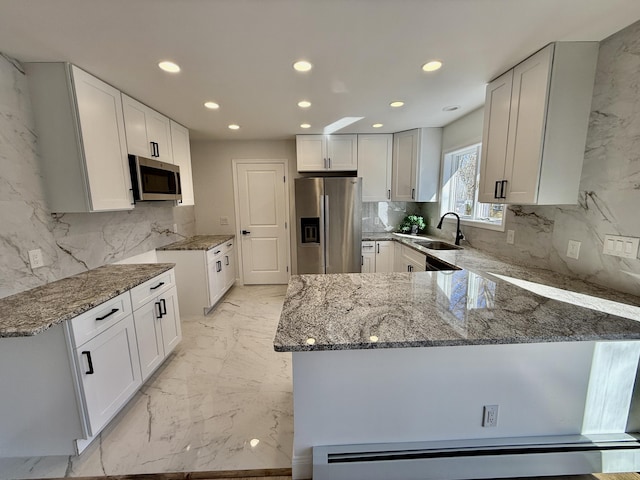 kitchen with stainless steel appliances, marble finish floor, a peninsula, and light stone counters