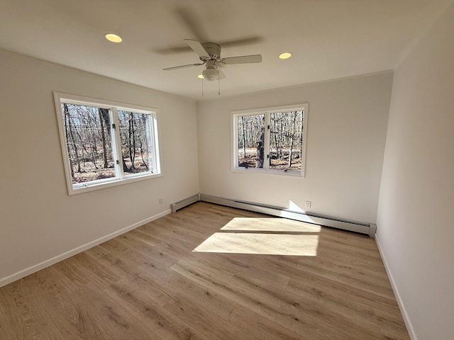 spare room with a baseboard heating unit, light wood-type flooring, baseboards, and recessed lighting