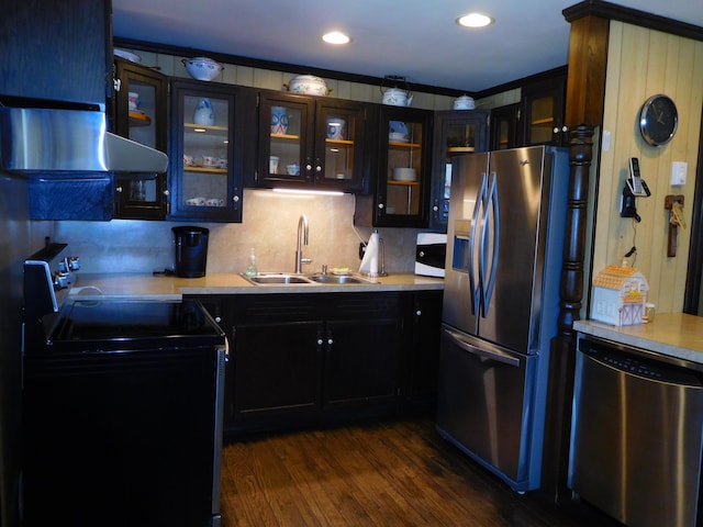 kitchen featuring dark wood-style flooring, appliances with stainless steel finishes, a sink, light countertops, and glass insert cabinets