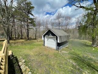 view of yard featuring a detached garage, an outbuilding, and a storage shed