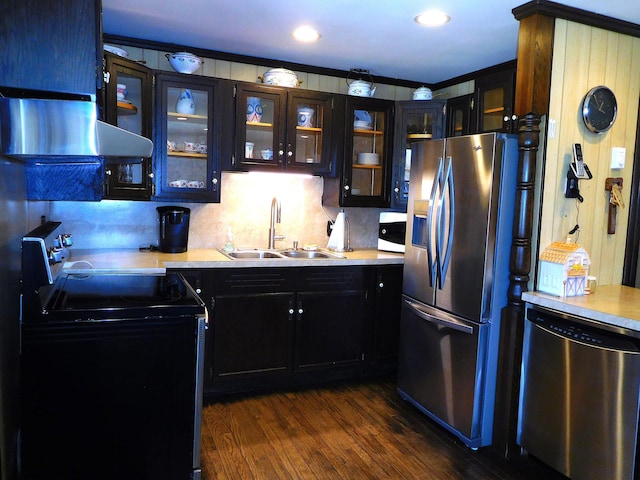 kitchen featuring glass insert cabinets, dark wood-style floors, light countertops, a sink, and appliances with stainless steel finishes