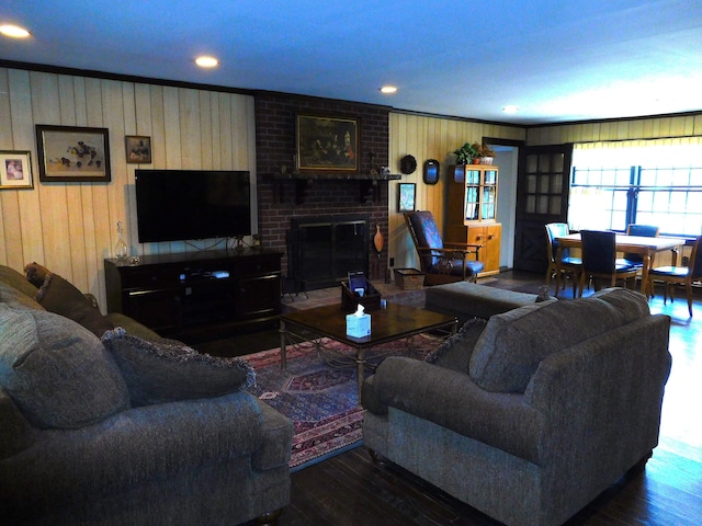 living area featuring wooden walls, crown molding, wood finished floors, and a fireplace